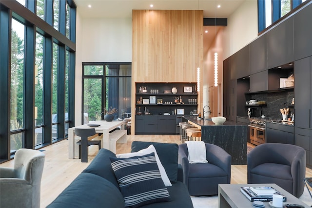 living room with recessed lighting, light wood-type flooring, and a towering ceiling