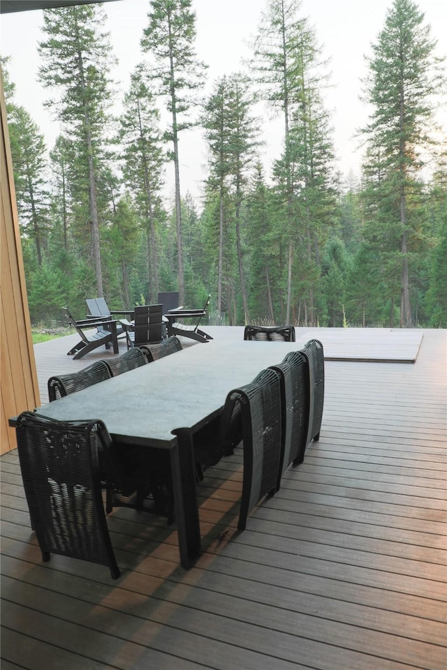 wooden terrace featuring a view of trees and outdoor dining area