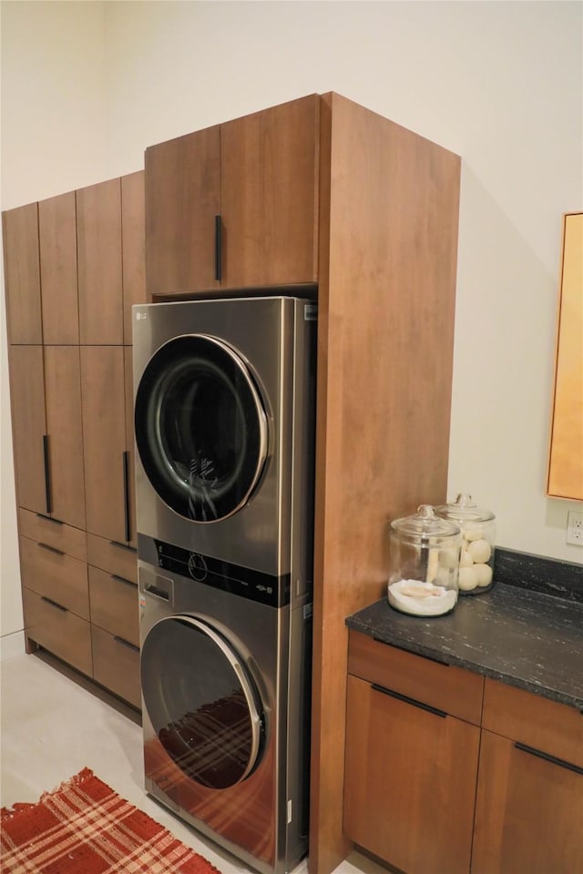 washroom featuring stacked washer and dryer and cabinet space
