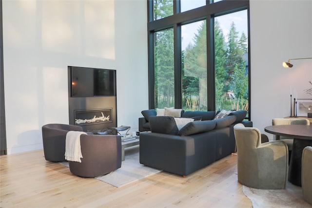 living room with light wood-style flooring and a towering ceiling