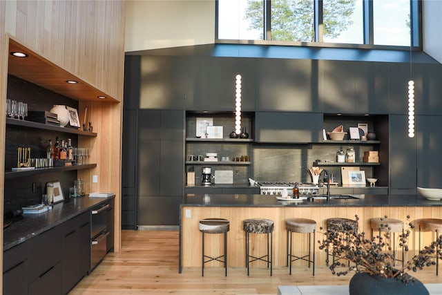 bar with a sink, tasteful backsplash, and light wood-style flooring