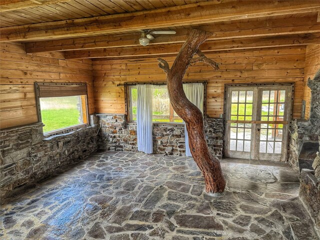 9536 Mt Highway 200, Plains, MT 59859 - unfurnished living room featuring wood ceiling, french doors, stone floors, beamed ceiling, and wooden walls