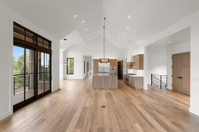 kitchen with high end appliances, open floor plan, high vaulted ceiling, light countertops, and light wood-style flooring