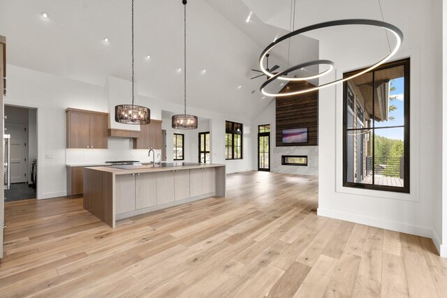 kitchen featuring an inviting chandelier, open floor plan, high vaulted ceiling, light wood-type flooring, and light countertops