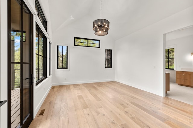 empty room with visible vents, high vaulted ceiling, baseboards, a chandelier, and light wood-style flooring