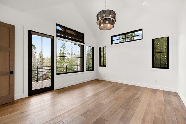 unfurnished room featuring baseboards, high vaulted ceiling, a wealth of natural light, and light wood-style flooring