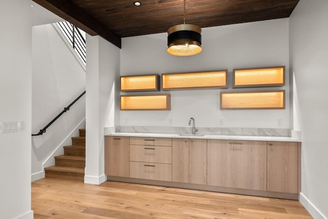 kitchen featuring light brown cabinetry, baseboards, wood ceiling, and light wood-style floors