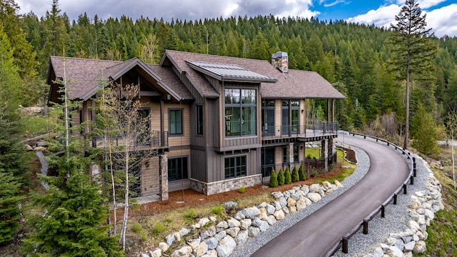 176 S Shooting Star Cir, Whitefish, MT 59937 - rear view of property with a view of trees, stone siding, a chimney, and roof with shingles