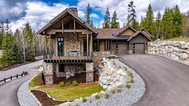 176 S Shooting Star Cir, Whitefish, MT 59937 - view of front facade with stone siding, a balcony, asphalt driveway, an attached garage, and a chimney