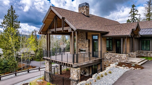 view of front of property with roof with shingles, fence, a balcony, and stone siding