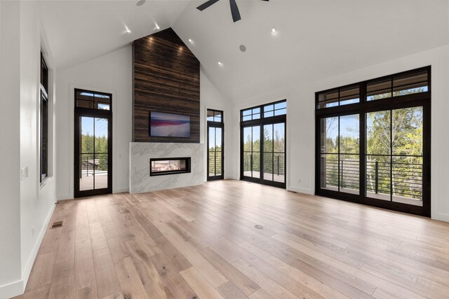 unfurnished living room featuring plenty of natural light, high vaulted ceiling, ceiling fan, and visible vents