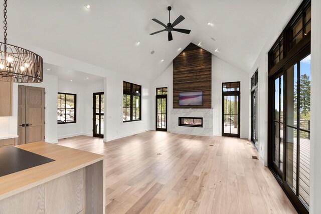 unfurnished living room featuring recessed lighting, ceiling fan with notable chandelier, a wealth of natural light, and high vaulted ceiling