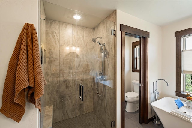 bathroom featuring toilet, a freestanding bath, a shower stall, and plenty of natural light