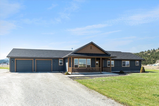 ranch-style house featuring roof with shingles, covered porch, gravel driveway, and a front yard