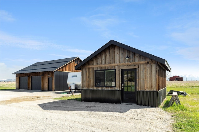 view of front of home with a detached garage, board and batten siding, and an outdoor structure