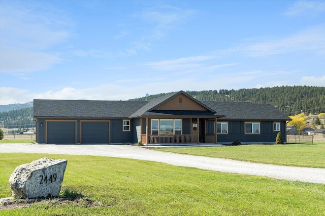 ranch-style home with fence, covered porch, a front yard, dirt driveway, and an attached garage