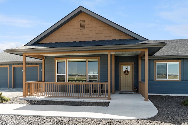view of front of house featuring roof with shingles, covered porch, an attached garage, and concrete driveway