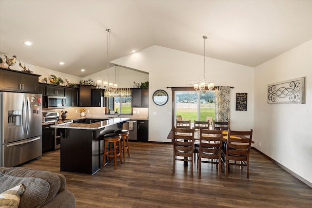 kitchen with a kitchen breakfast bar, a kitchen island, decorative light fixtures, appliances with stainless steel finishes, and an inviting chandelier