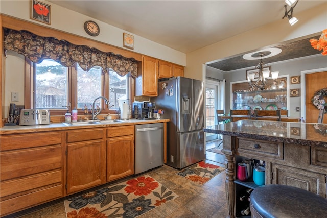 kitchen with appliances with stainless steel finishes, a sink, a chandelier, plenty of natural light, and ornamental molding