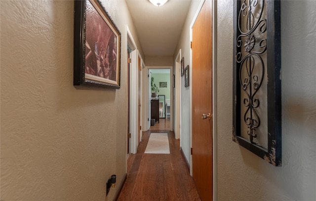 hall featuring a textured wall and wood finished floors