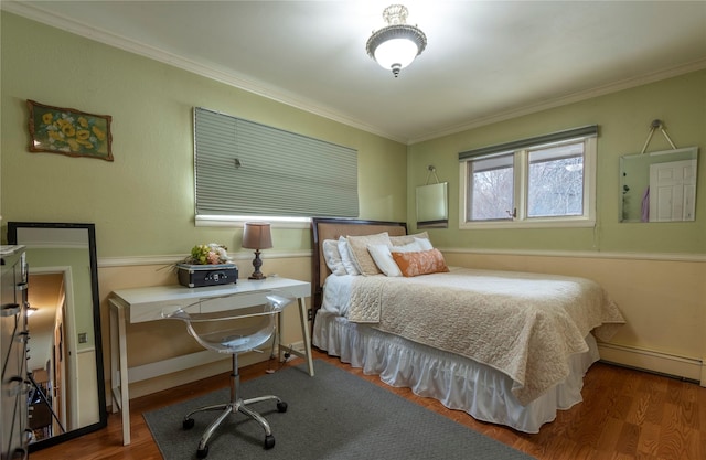 bedroom with wood finished floors, baseboard heating, ornamental molding, an office area, and baseboards