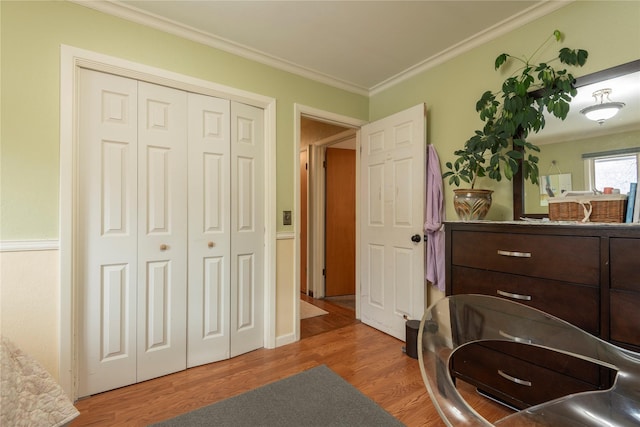 bedroom with ornamental molding, wood finished floors, and a closet