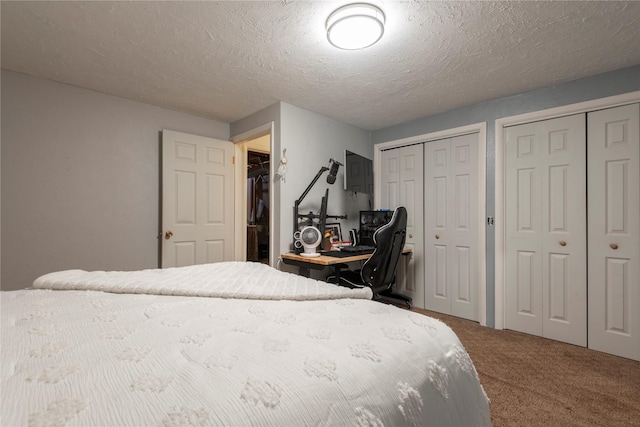 bedroom with two closets, carpet, and a textured ceiling