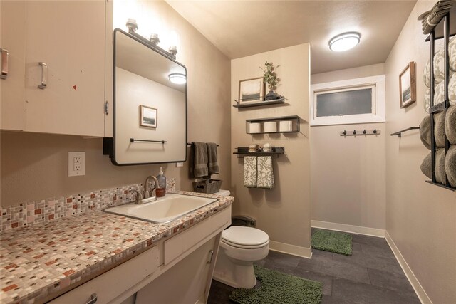 bathroom featuring toilet, baseboards, vanity, and tile patterned flooring