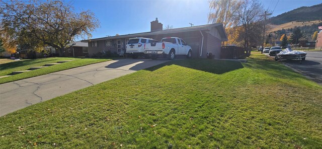 view of front facade with a chimney, driveway, and a front yard