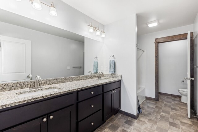 1521 Cheery Dr, Belgrade, MT 59714 - bathroom featuring double vanity, a sink, baseboards, and toilet