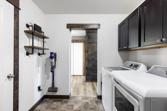 1521 Cheery Dr, Belgrade, MT 59714 - clothes washing area with stone finish floor, visible vents, cabinet space, baseboards, and separate washer and dryer