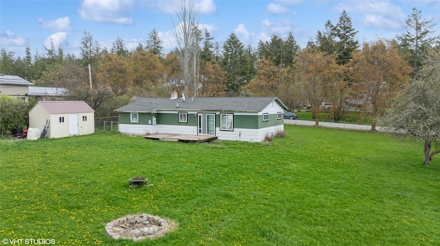 rear view of property featuring a lawn, a deck, fence, and a storage shed