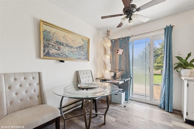 dining area with baseboard heating, a ceiling fan, and wood finished floors