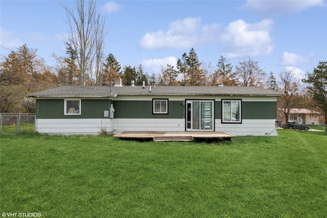 rear view of property featuring a yard, a deck, fence, and roof with shingles