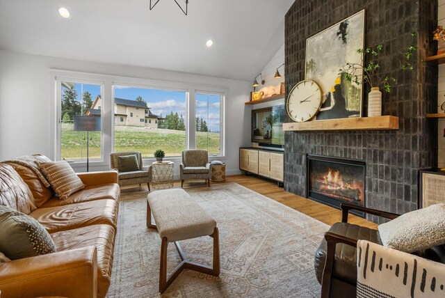 living area with a fireplace, recessed lighting, wood finished floors, and lofted ceiling