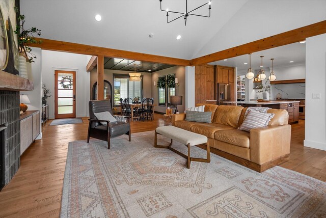 living room with a chandelier, recessed lighting, baseboards, light wood-type flooring, and vaulted ceiling