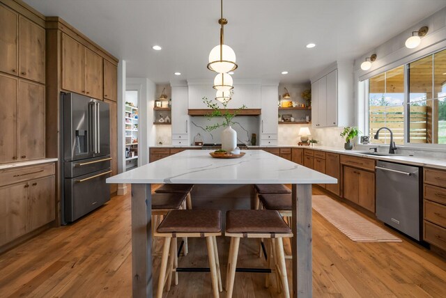 kitchen featuring recessed lighting, open shelves, brown cabinetry, and appliances with stainless steel finishes