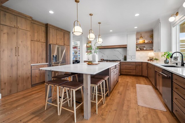 kitchen featuring a sink, open shelves, stainless steel appliances, and light wood-type flooring