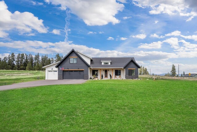 modern farmhouse featuring roof with shingles, an attached garage, a front lawn, covered porch, and driveway