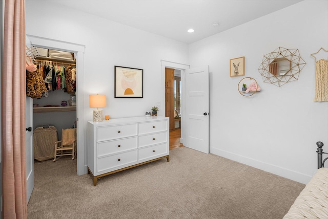 bedroom featuring a closet, light carpet, baseboards, a walk in closet, and recessed lighting