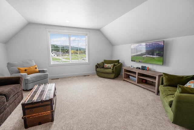 carpeted living area with baseboards and vaulted ceiling