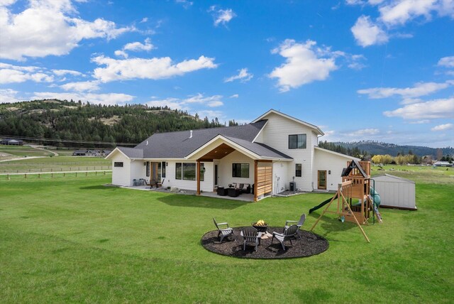 rear view of house featuring a lawn, a patio area, fence, a shed, and a playground