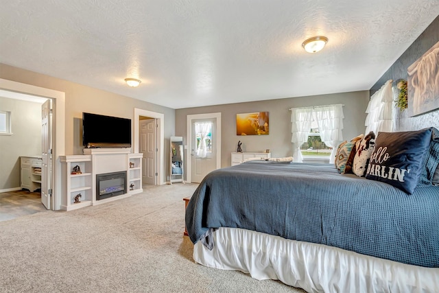 bedroom featuring a glass covered fireplace, baseboards, carpet flooring, and a textured ceiling