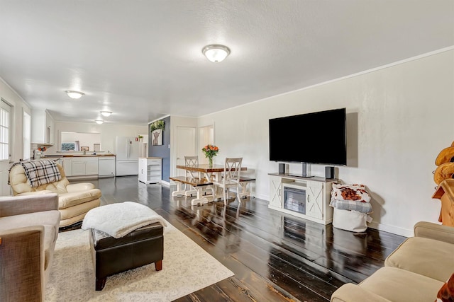 living area with crown molding, baseboards, and dark wood-style flooring
