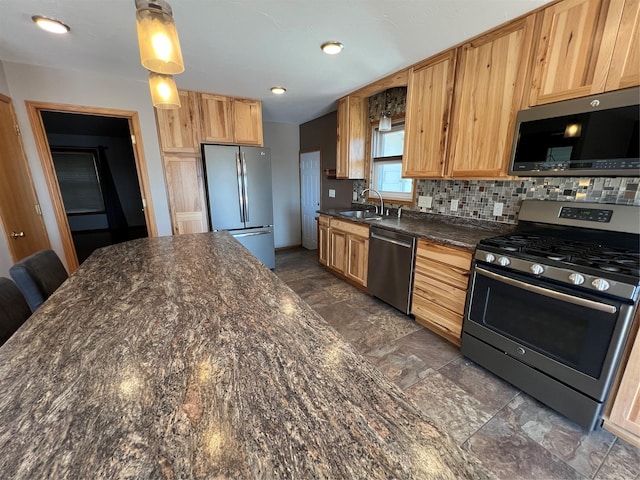 kitchen with decorative backsplash, appliances with stainless steel finishes, a sink, dark stone countertops, and light brown cabinets