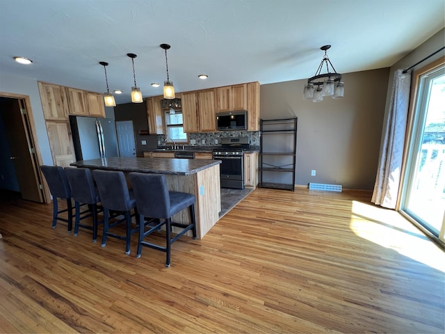 kitchen with dark countertops, appliances with stainless steel finishes, plenty of natural light, and light wood-style floors