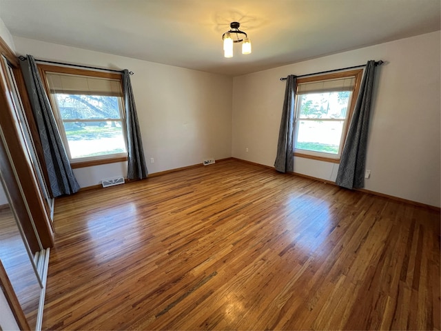 unfurnished room featuring visible vents, baseboards, and wood finished floors