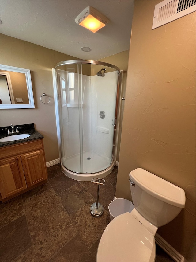 bathroom featuring vanity, toilet, stone finish flooring, a shower stall, and visible vents