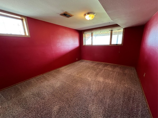 carpeted spare room with visible vents and a textured ceiling