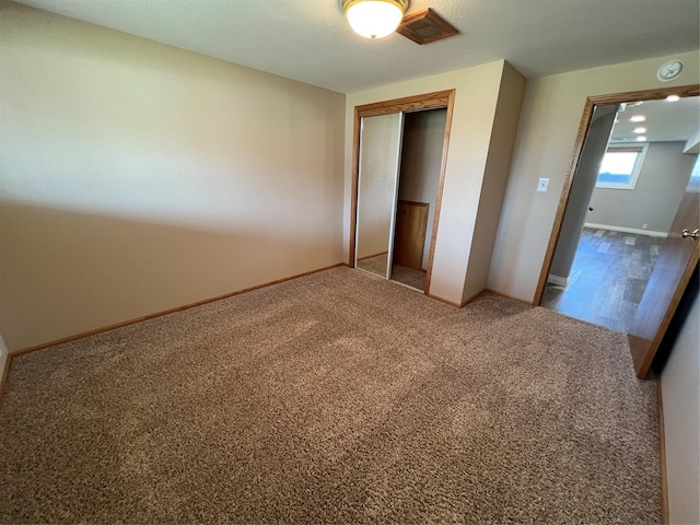 unfurnished bedroom with baseboards, carpet, and a closet